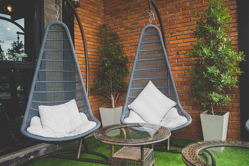 Balcony chair and table set with wicker or woven wood straddle occupying green balcony