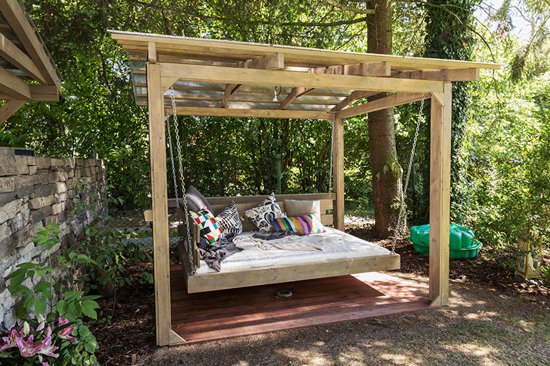 Outdoor garden design with a swing daybed and plenty of pillows