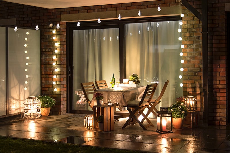 Outdoor lighting design with fairy lights and candle lights on the table and outdoor wall design with magic lights