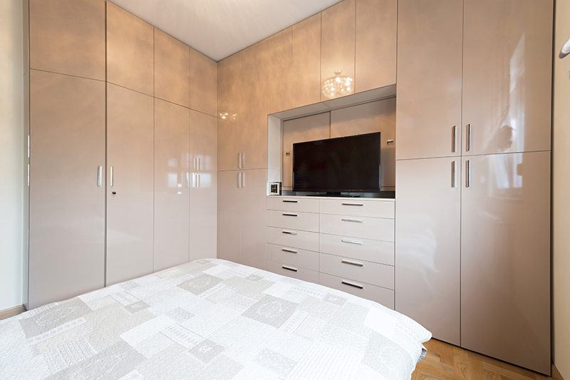 Ceiling to floor wardrobe design with a tv cabinet extends across both bedroom walls