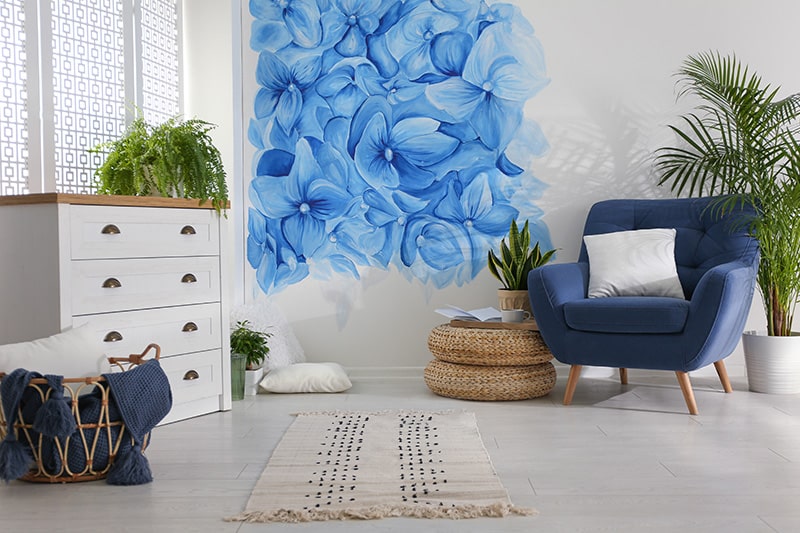 The floral carolina blue living room design with blue floral patterns painted on the wall look artistic and stylish