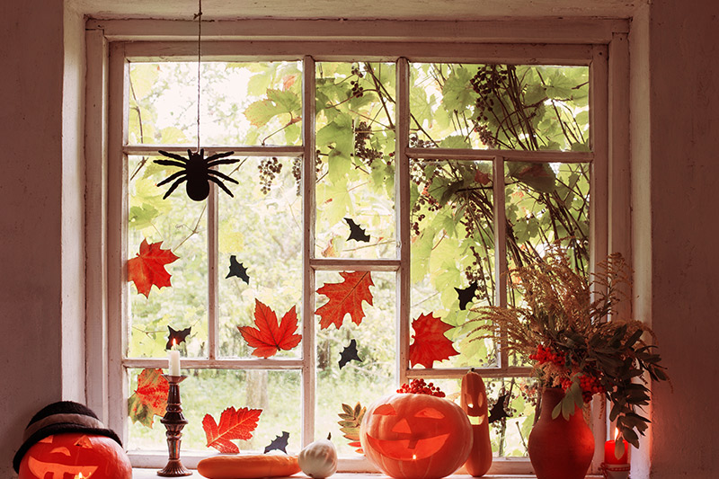 Halloween window decoration ideas add orange and brown leaves look rustic and blend in well with pumpkins.