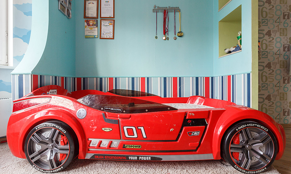 Modern kids bed design where a red-hot bed displays black rims, and a comfortable mattress Caption: