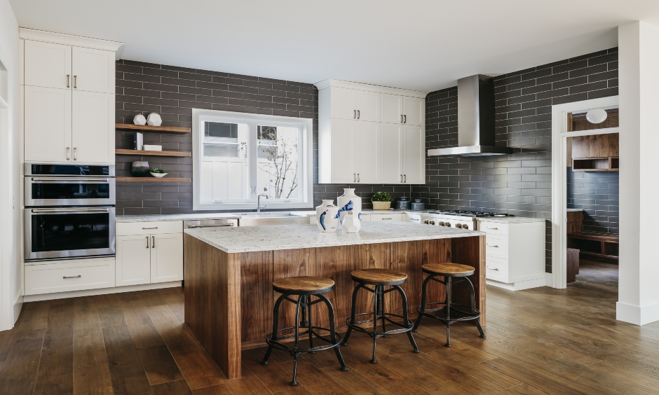 Industrial kitchen island with stainless steel chimney, dark wooden bar chairs brings out an industrial vibe.