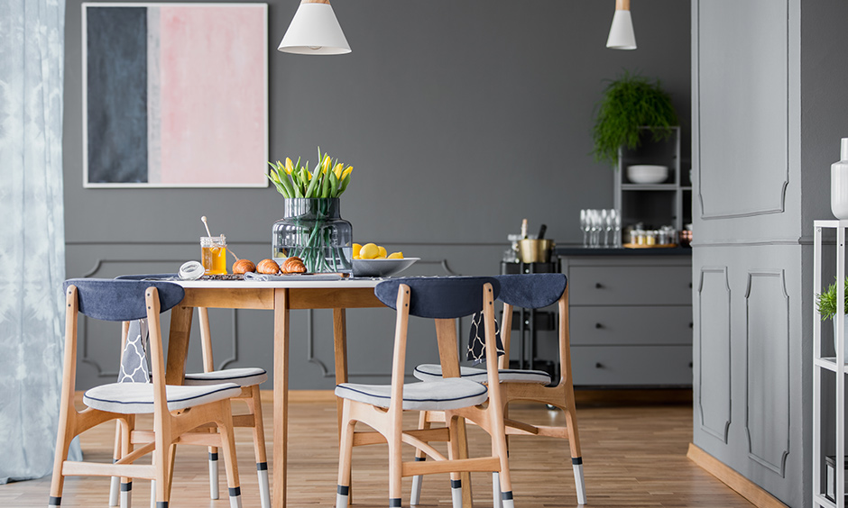 A Dining room design that has grey walls and has pendant lights to add a bit of warmth