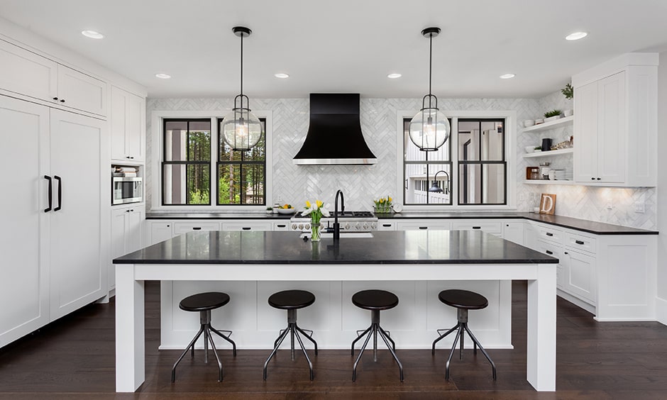 Luxurious black and white kitchen design with black island countertops, stools and sleek white cabinets