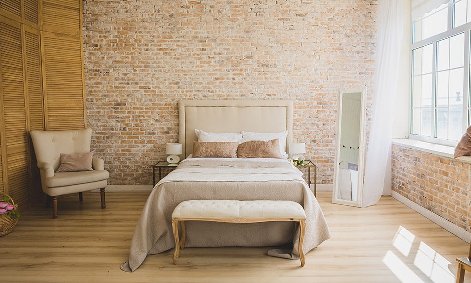 Rustic style minimalistic bedroom design with a queen-sized wooden bed and an exposed brick wall