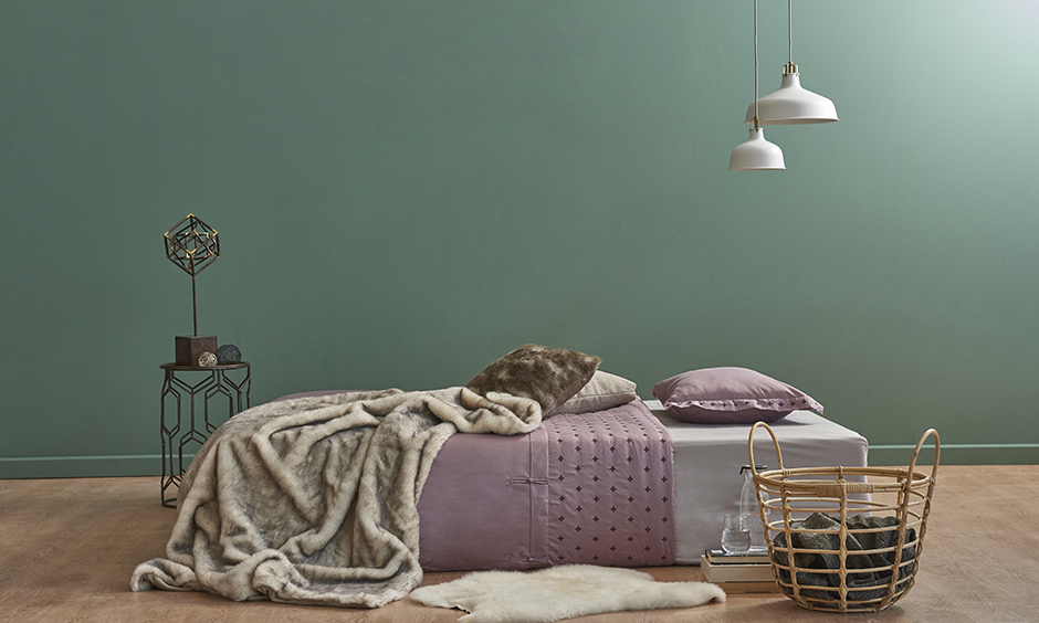 Green and lavender bedroom with unique light fixtures and a furry rug