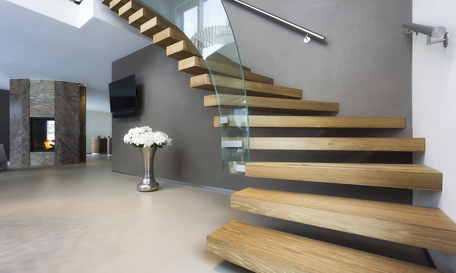 Twisted wooden staircase with floating steps and a glass railing brings a modern wooden staircase design