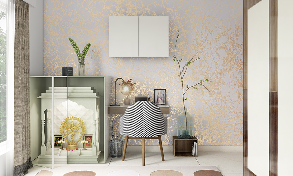 A pale white and gold wallpaper creates the right kind of aura around the pooja unit and study table