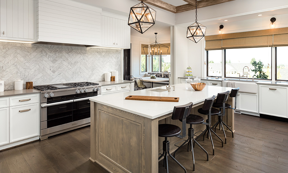 This kitchen island lighting has drop-down light above a countertop & antique candle styled light above a dining table.