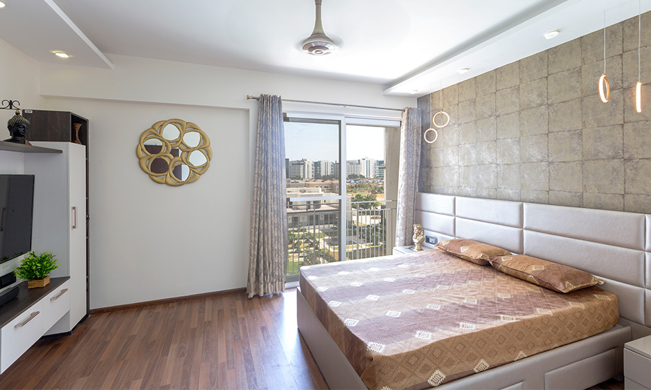 This Guest room has wooden flooring, wall mirror & rustic square wallpaper are the best interiors in Bangalore.