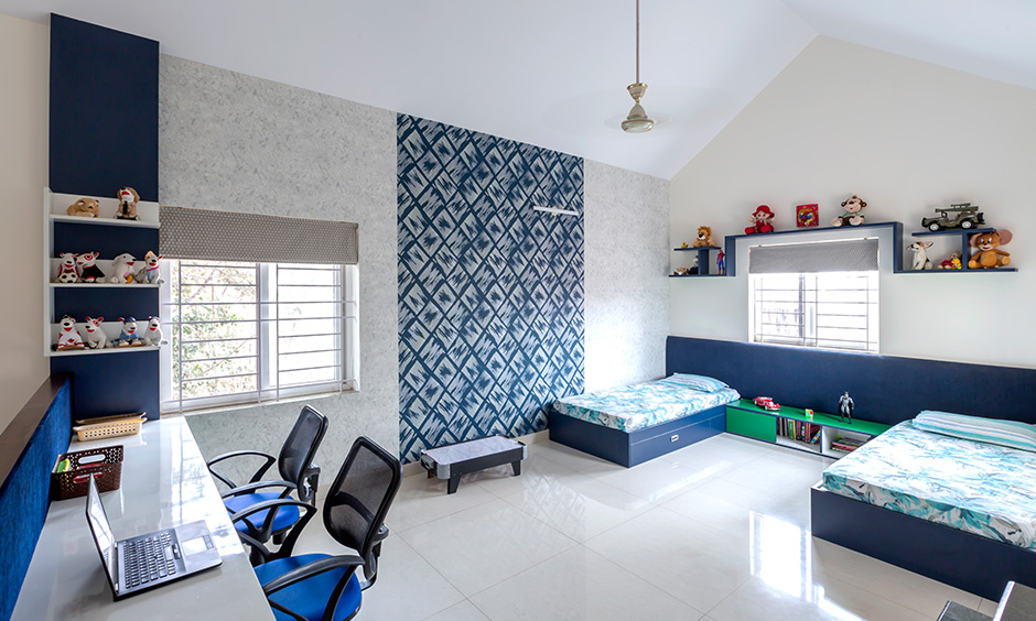 DC best interior designers in sarjapur road designed this kids room with study table, blue pattern wallpaper & blue beds.