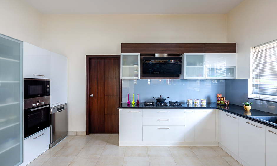 White u-shaped kitchen designed by dc interior designers in sarjapur road with all the essential storage looks modern.