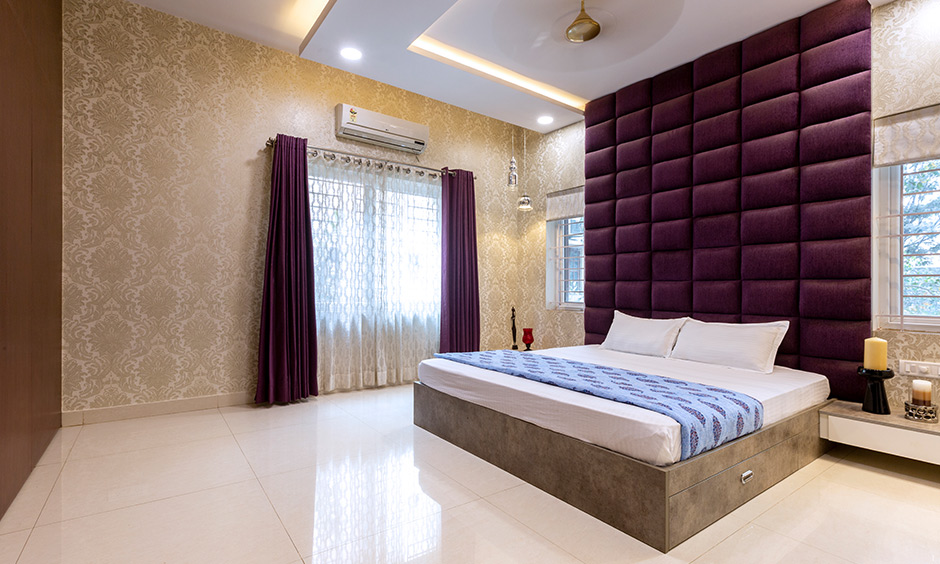 Master bedroom with purple upholstered headboard & gold wallpaper intricate Victorian pattern interior design Bangalore Sarjapur Road.