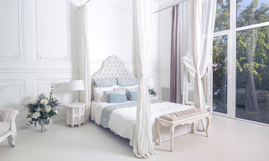 A white four poster bed design in a victorian style in all-white bedroom