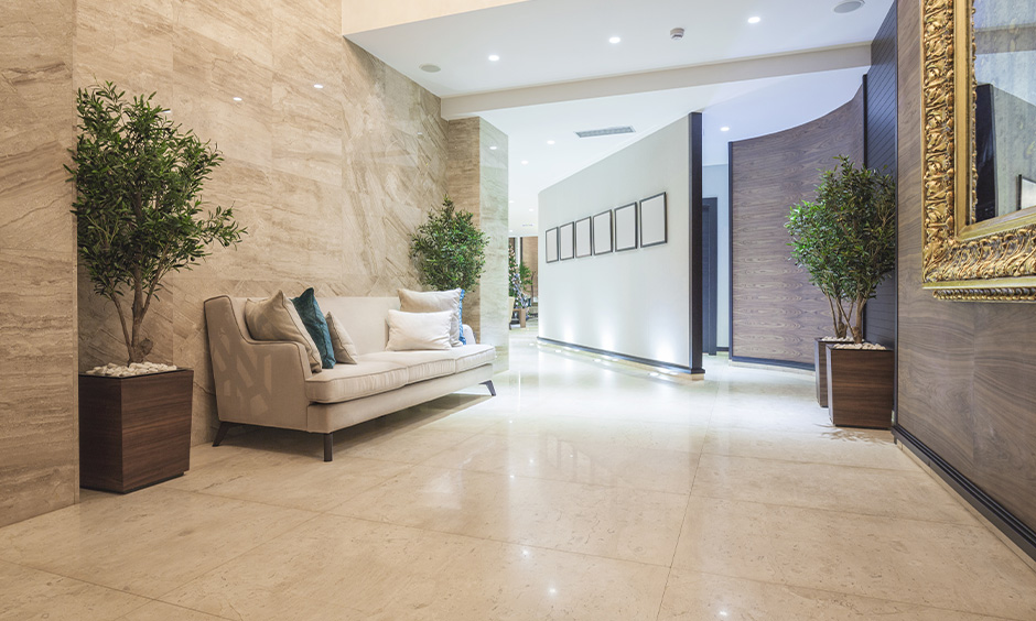 This lobby decoration in the passageway with indoor plants, sofa & false ceiling with recessed lighting is gorgeous.