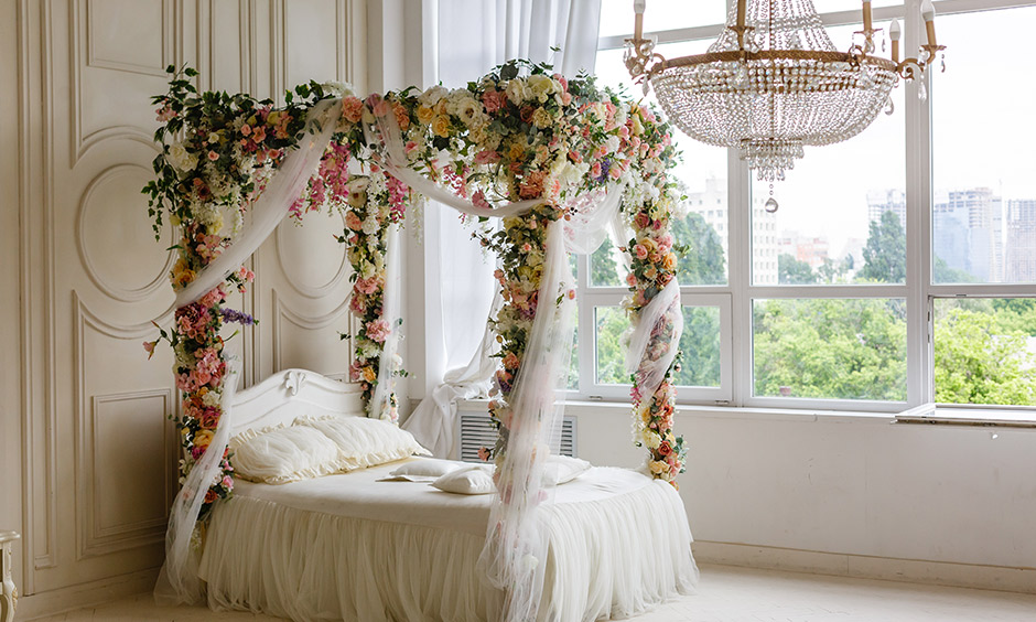 A four poster bed curtains decorated with a fresh flower in the white bedroom