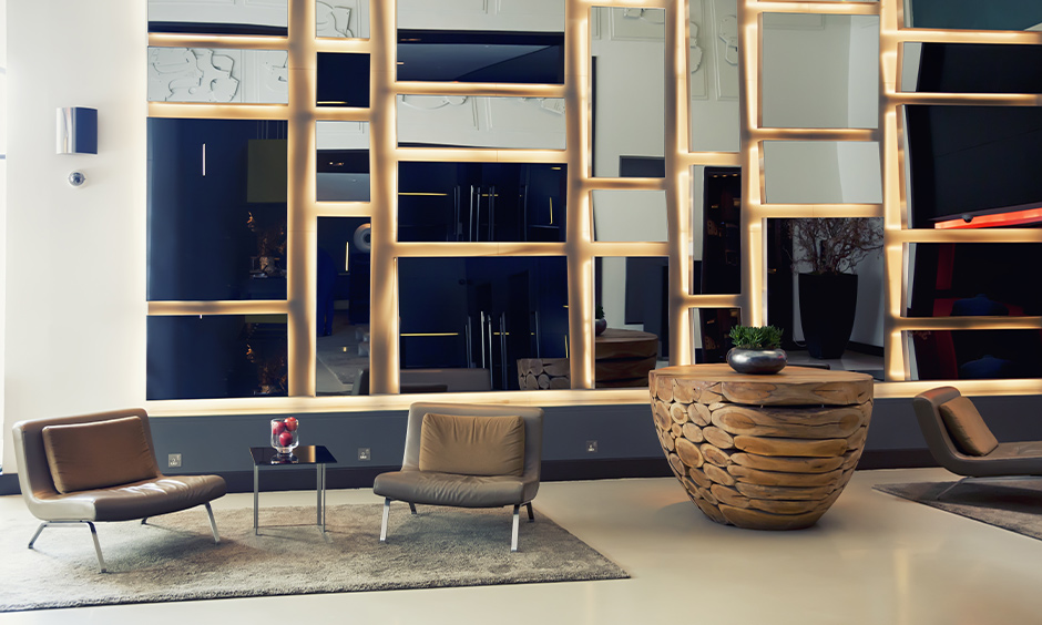 This lobby wall design with the mirror & lighting behind looks edgy and abstract with two cushion chairs.