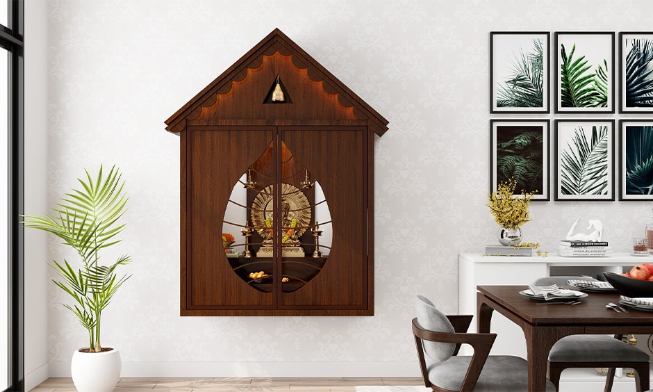 Simple wall mounted mandir design with dark wood doors in a leaf shape design