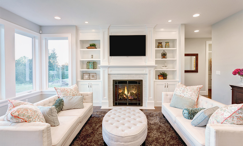 A built-in cupboard design in frosty white with shelves is an elegant tv cupboard design in the hall