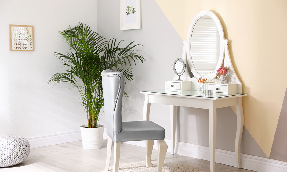 Victorian-styled white wooden dressing table designs with oval mirror, a console table & drawers look elegant.