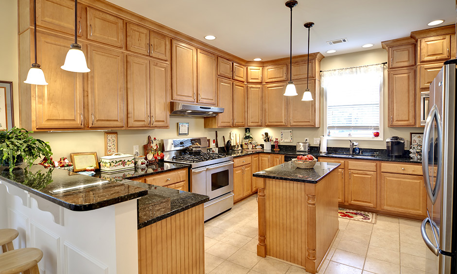 Glossy black granite countertops with cream white flooring make this kitchen look warm yet luxurious.