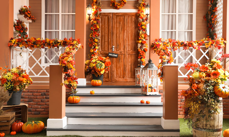 Halloween door decorations with spooky face pumpkins and fall autumnal leaves