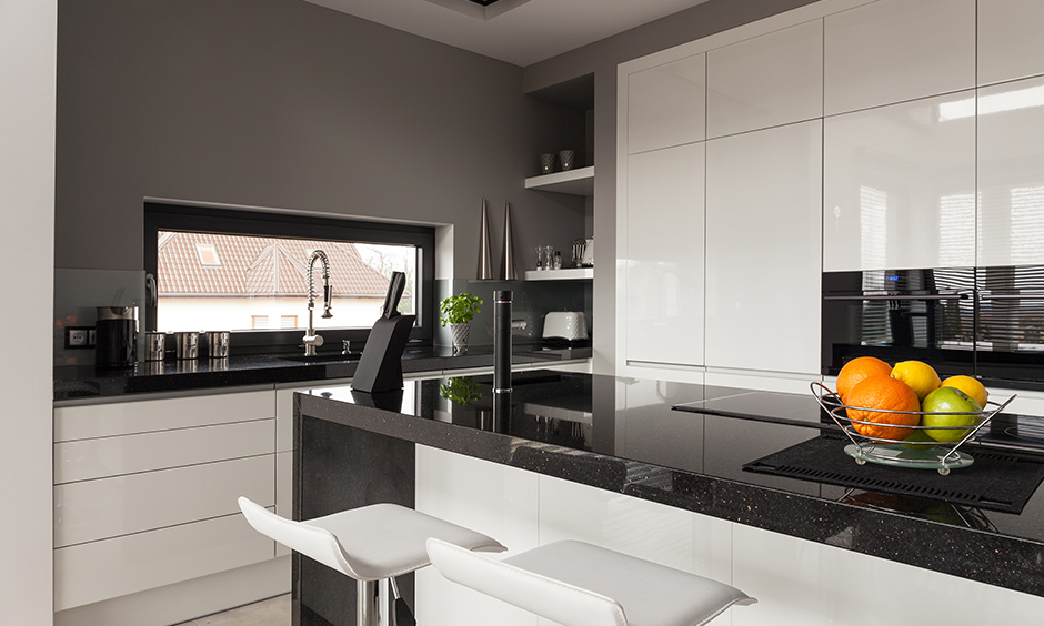 High glossy black granite countertops in kitchen with white cabinets and deep grey walls look stunning.