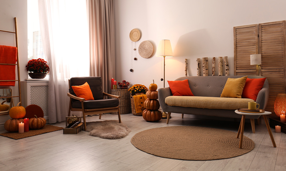 Halloween theme decoration for living room with cushions in fall colours, pumpkins and candles