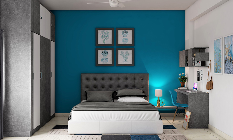 Dark teal colour paint on one accent wall pairs well with grey accents and creative wall paintings in the bedroom.