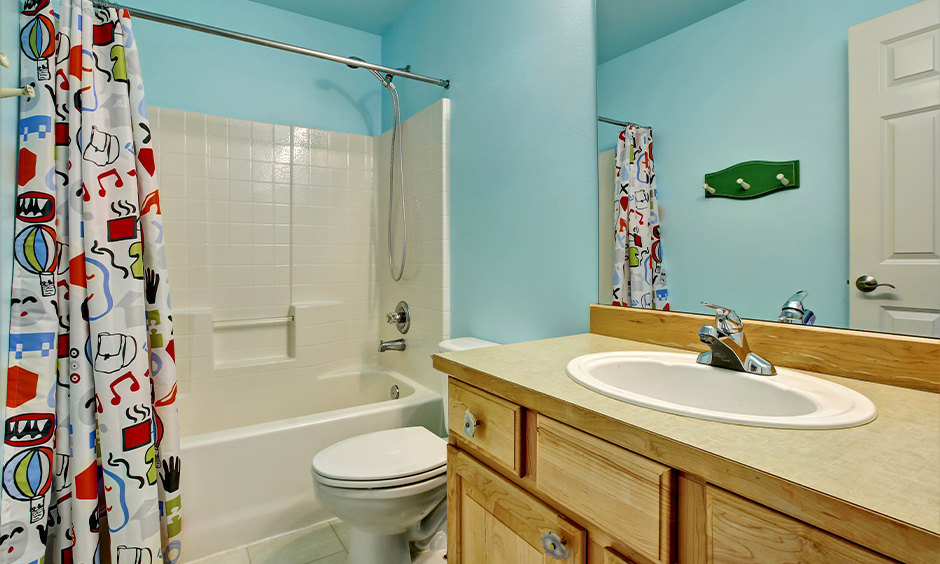 Kids bathroom ideas bathtub with a child-friendly grab bar and cartoon shower curtain add some playfulness to the area.