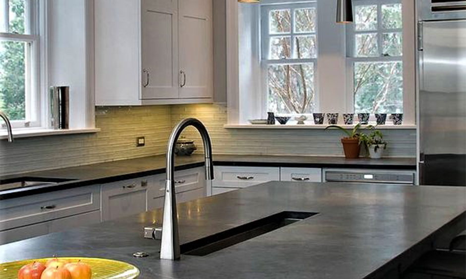 Black soapstone countertops which embellishes the grey and off-white kitchen 