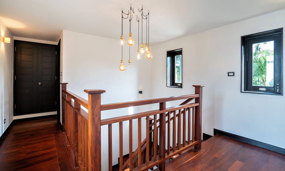 Classic indoor wood stair railing design with industrial hanging lights above accentuate and ooze warmth into space.