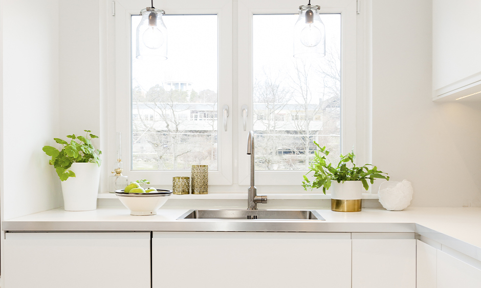 The classy white window makes it look more spacious in this white kitchen window design in India with hanging lights.