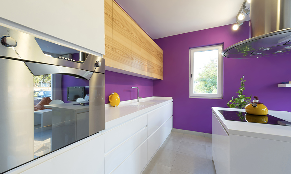 A mix of retro and modern kitchen with purple wall and white cabinets add a cosy charm are the purple kitchen design ideas.