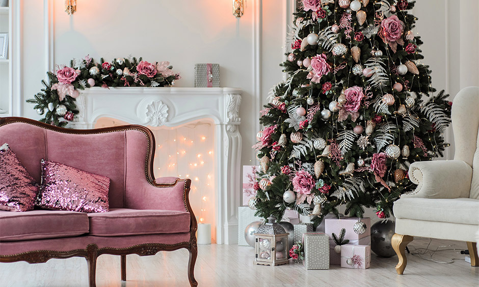 Christmas tree decoration with artificial pink roses, bright ball and pine cone ornaments.