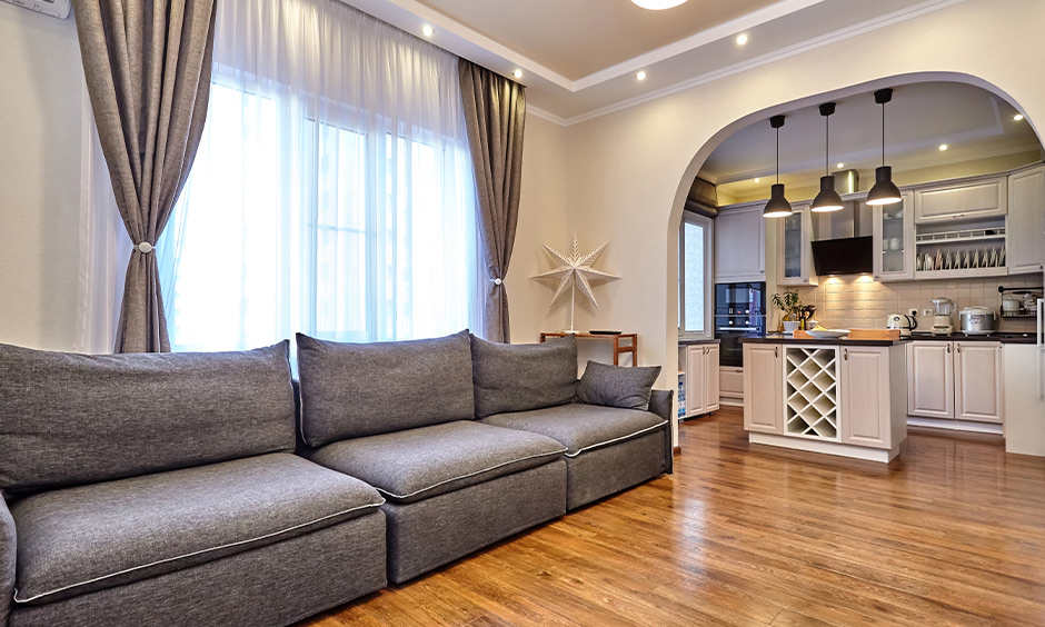 Corner island small open kitchen with living room design in India in white colour looks minimalistic.