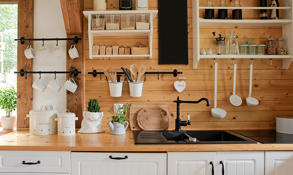 Two hanging kitchen shelves in white with hooks against the wooden wall brings in a farmhouse kitchen look.