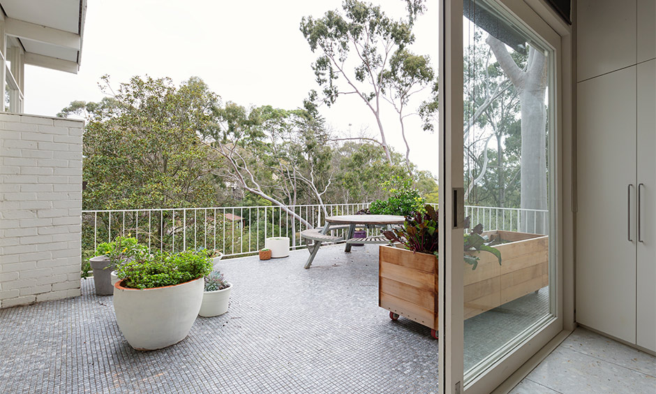 Mosaic balcony tiles design in India with round seating surrounded by potted plants brings a fresh vibe.