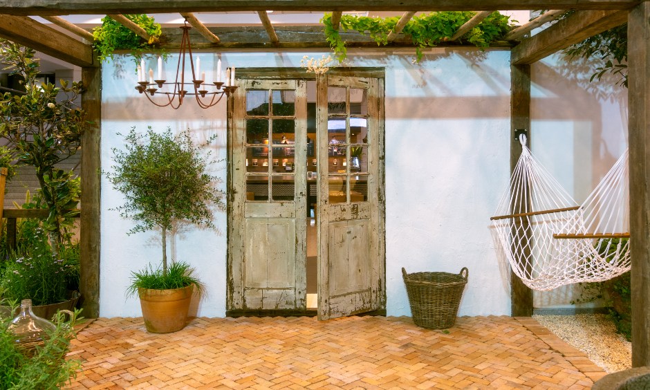 Small terrace garden design in a rustic theme with a hammock aligned with lush planters looks elegant.