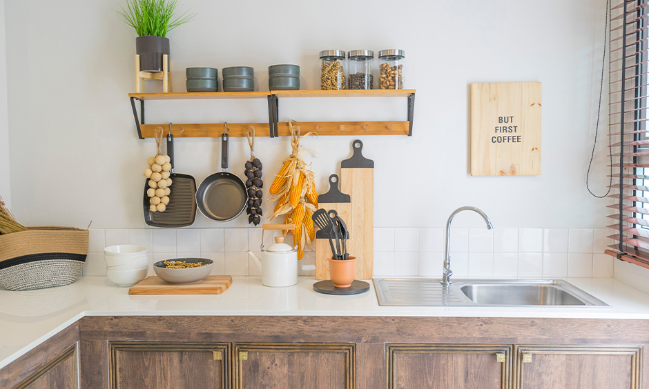 Wall hanging kitchen shelves with hooks made from wooden panels and metal to storage spice jars on and also indoor plants.