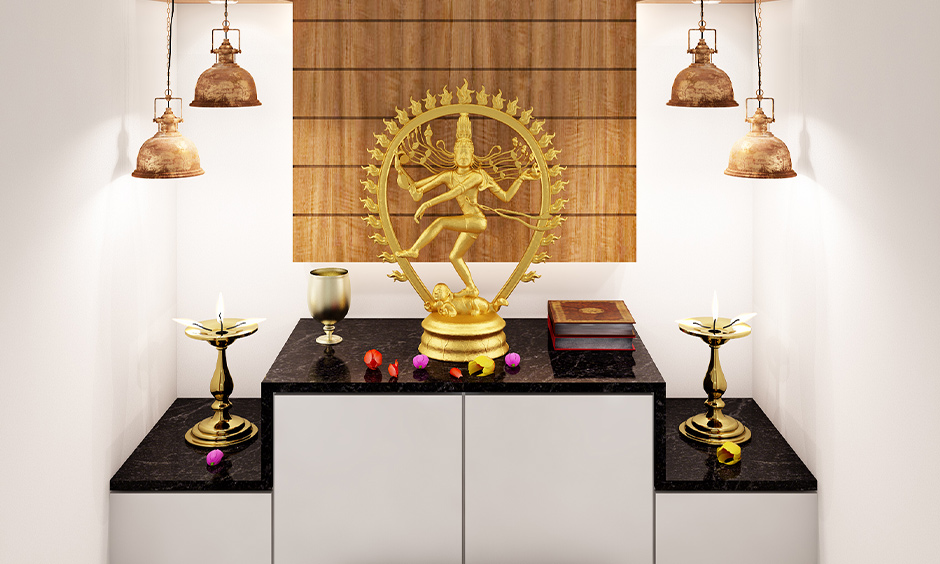 A south indian styled small pooja room designs in apartments with white vitrified flooring and a black granite countertop