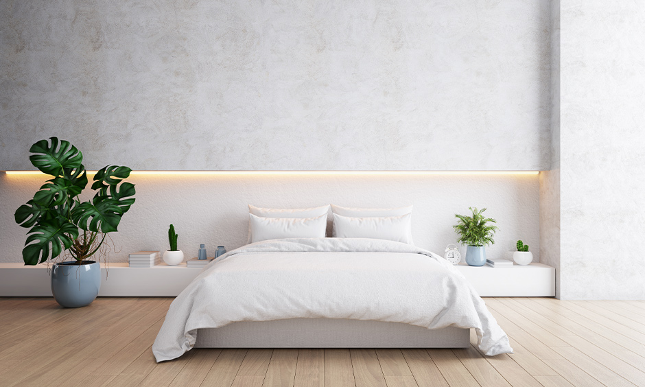 The all-white bedroom has bed wall lights behind the bed