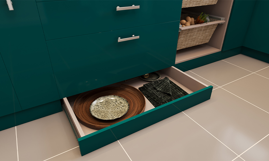 Best kitchen storage designed in a green laminated skirting drawer under the base unit stored with cleaning cloths and paper bags.