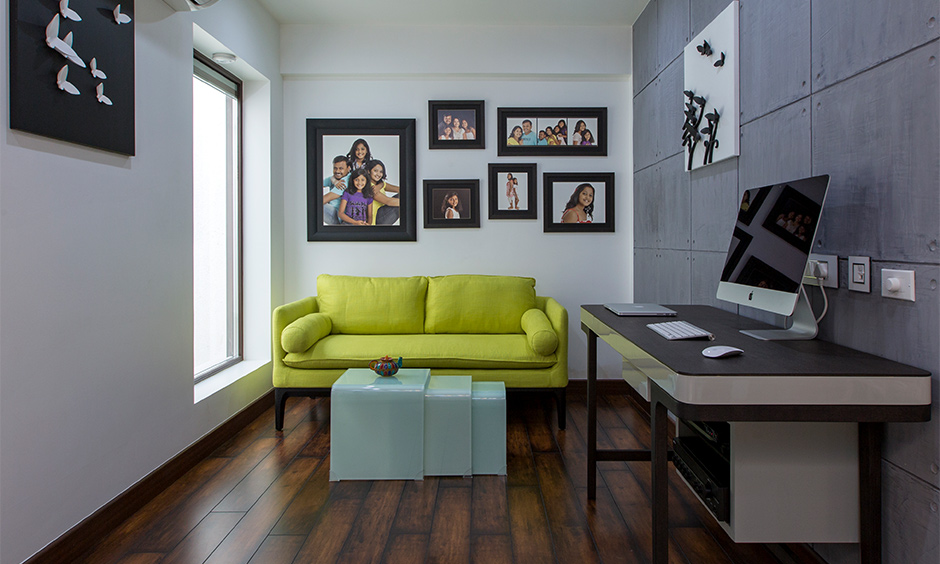 Study room designed with a yellow couch, desk and wooden flooring in Tumkur road home designed by design cafe.