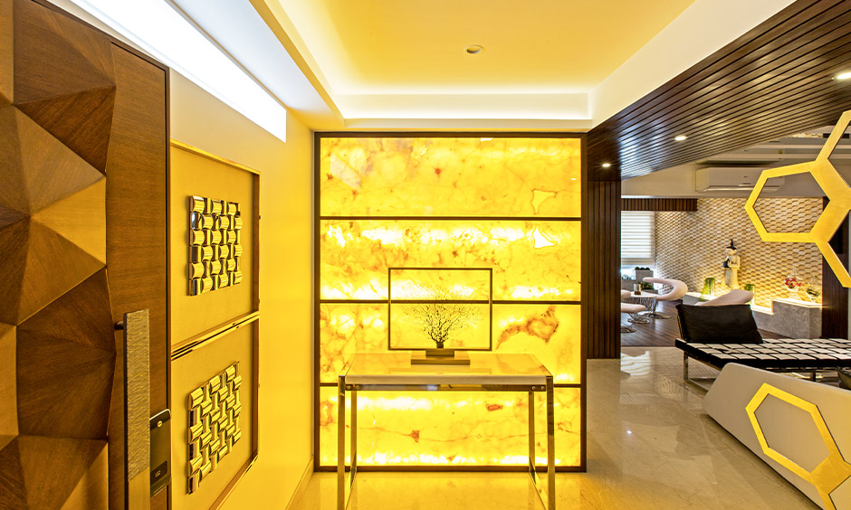 Tumkur road home designed with a foyer area with a yellow alabaster sheet with lights at the back creates a warm welcome.