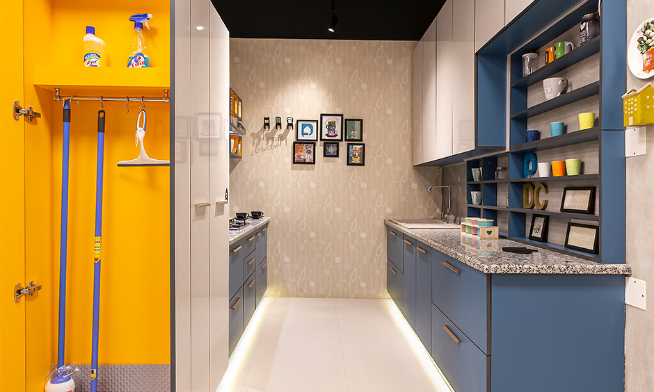 Design cafe experience centre, Parallel kitchen with blue and white laminate cabinets and janitor unit brings joyful.