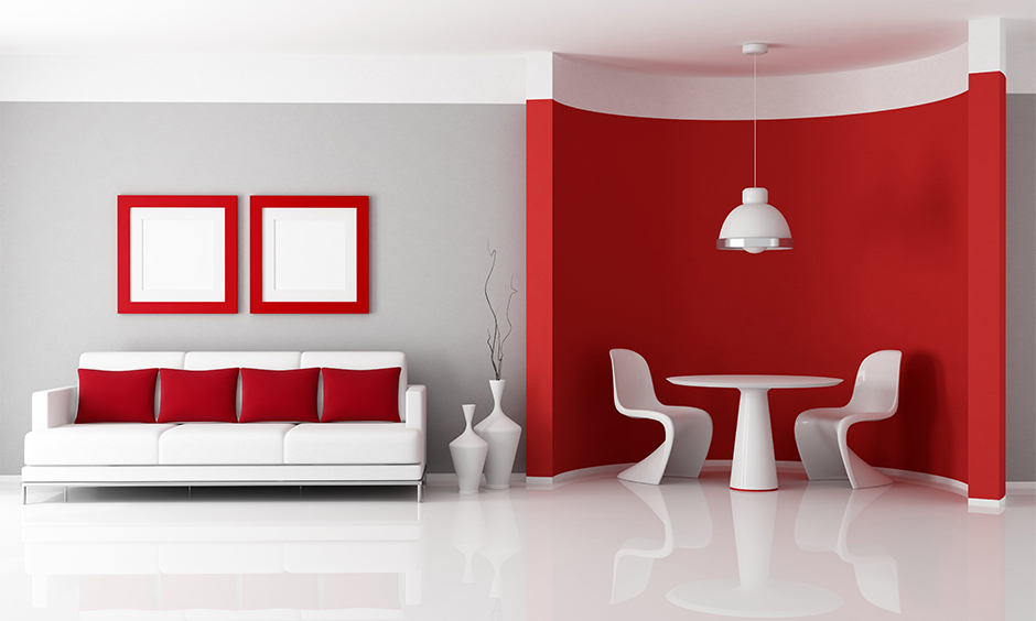 Half grey and half red wall living room with white round table and sofa emphasise the red in the room.