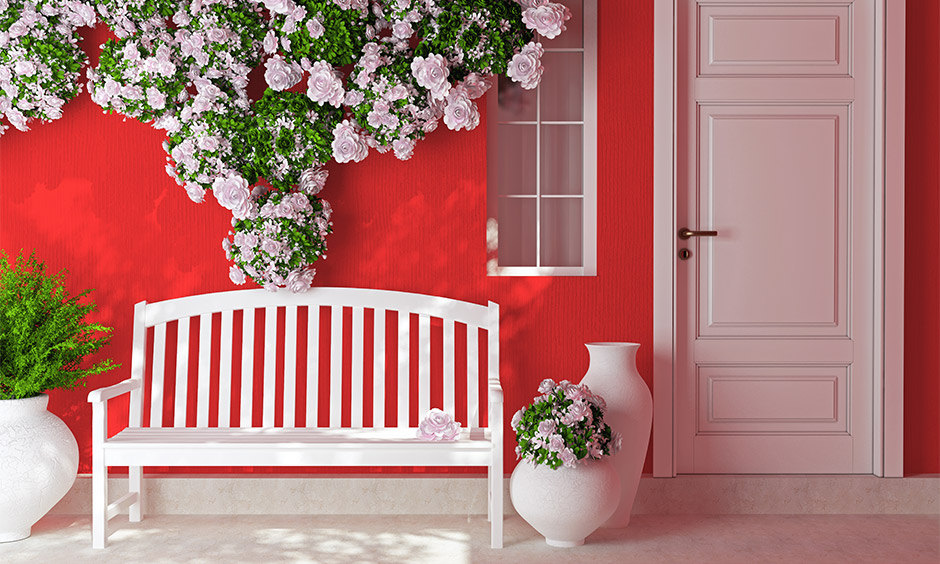 DIY valentines decorations for home entrance, front porches decorated with wooden patio bench and flowers on a red wall.